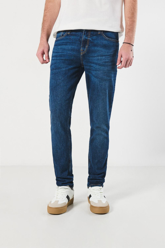 Jean azul oscuro slim con desgastes sutiles y tiro bajo