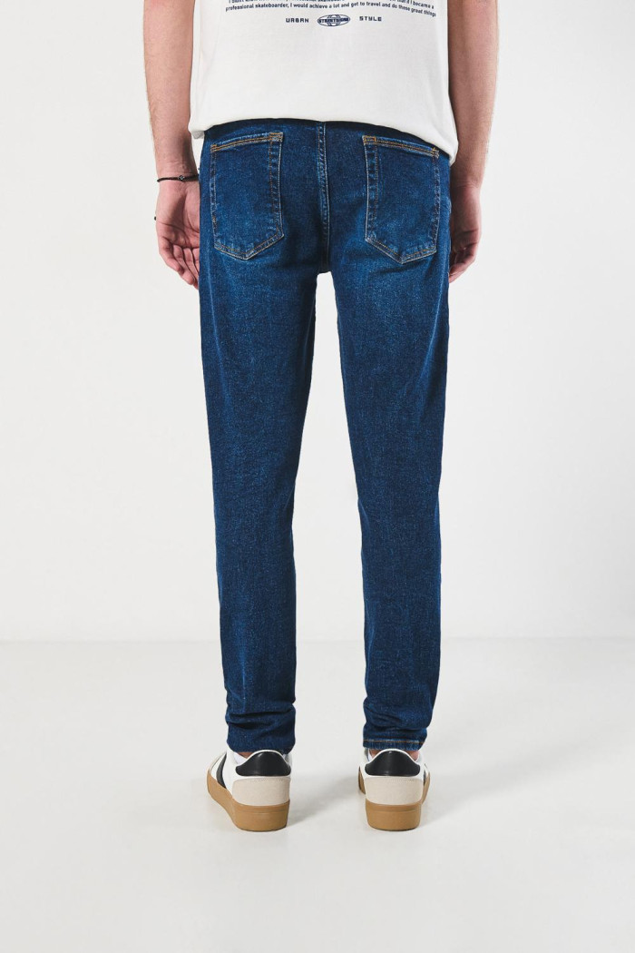 Jean azul oscuro slim con desgastes sutiles y tiro bajo