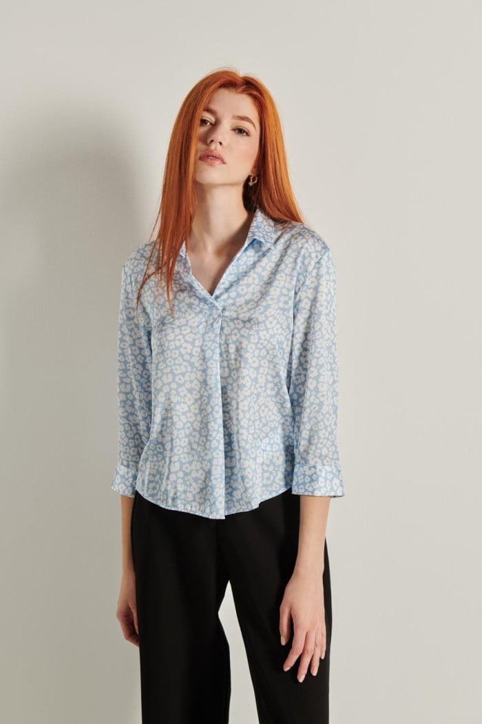 Blusa azul con cuello camisero, manga 3/4 y flores blancas