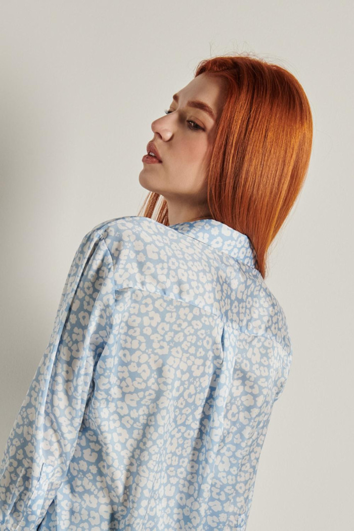 Blusa azul con cuello camisero, manga 3/4 y flores blancas
