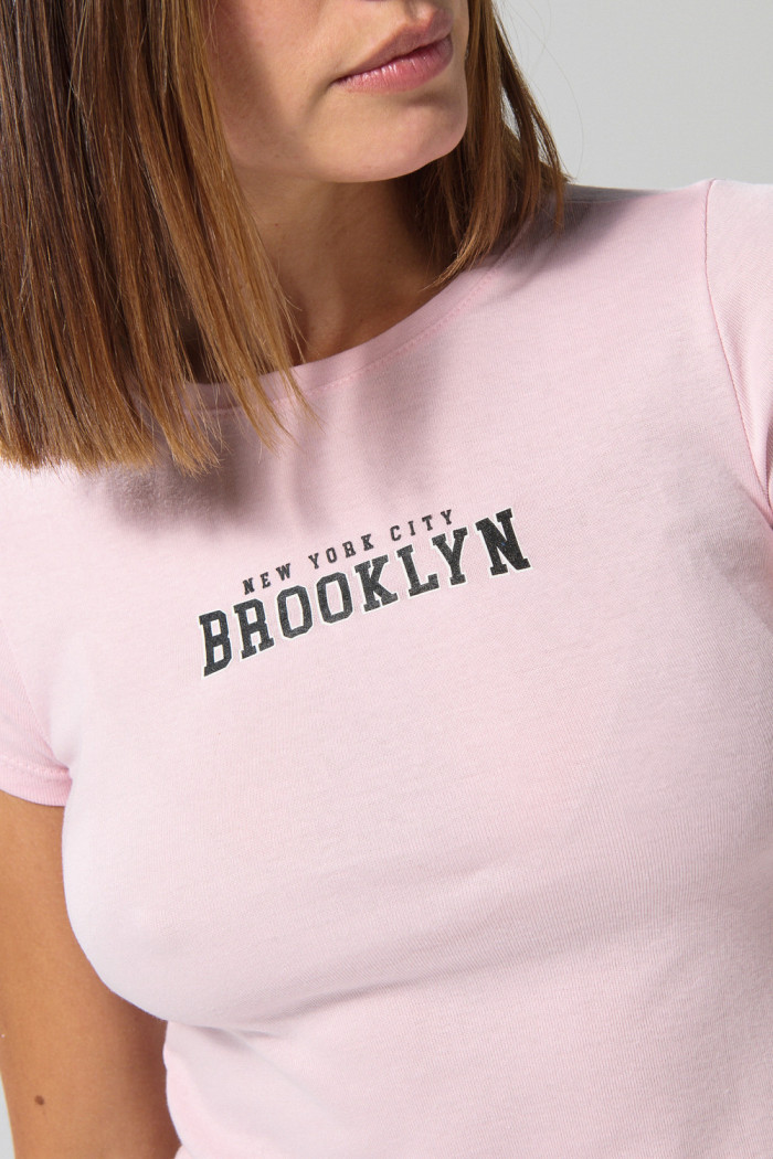 Camiseta rosada clara cuello redondo con texto college