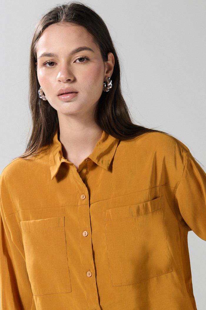 Blusa unicolor con doble bolsillo, manga larga y botones