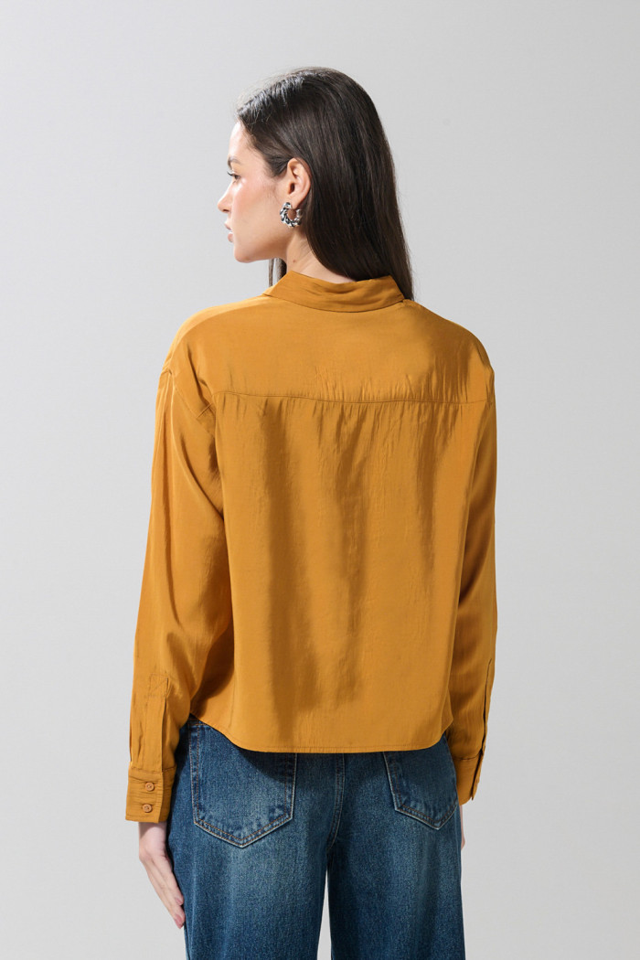 Blusa unicolor con doble bolsillo, manga larga y botones