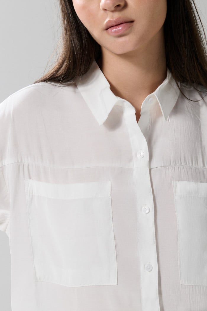 Blusa unicolor con doble bolsillo, manga larga y botones