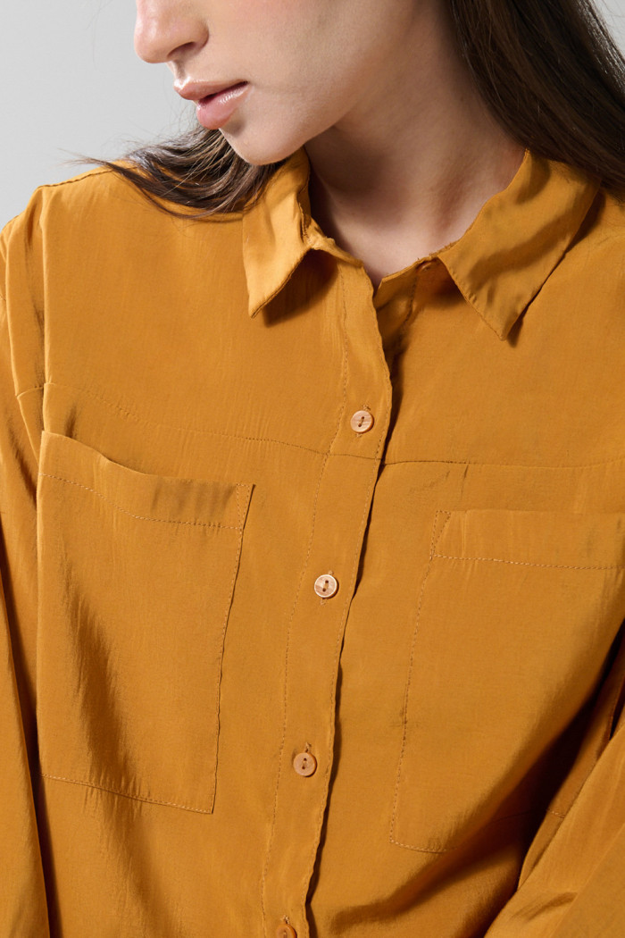 Blusa unicolor con doble bolsillo, manga larga y botones