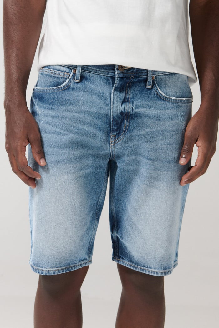 Bermuda en jean azul clara tipo slim con rotos y tiro bajo