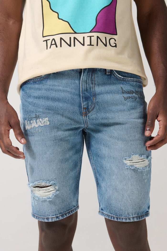Bermuda slim tiro bajo en jean azul con rotos y diseños