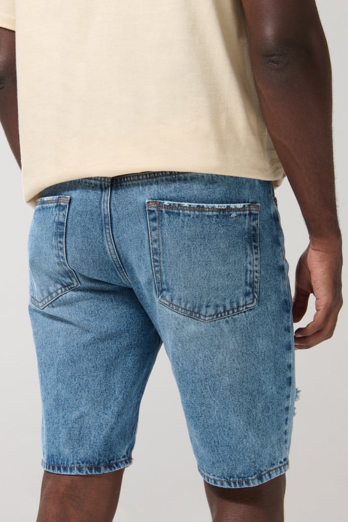 Bermuda slim tiro bajo en jean azul con rotos y diseños