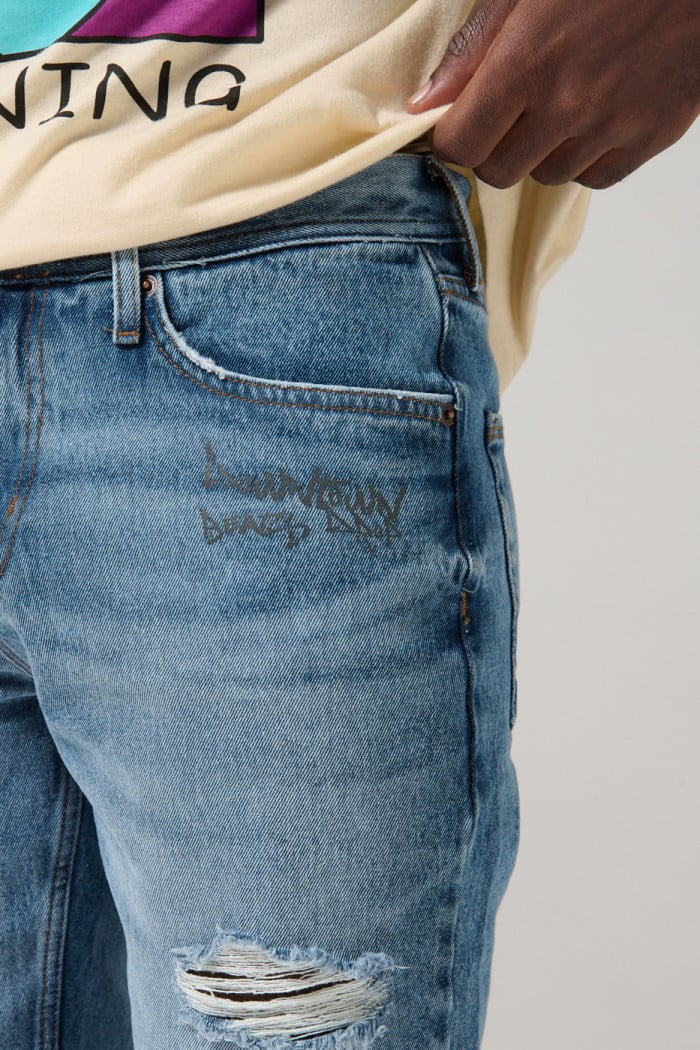 Bermuda slim tiro bajo en jean azul con rotos y diseños