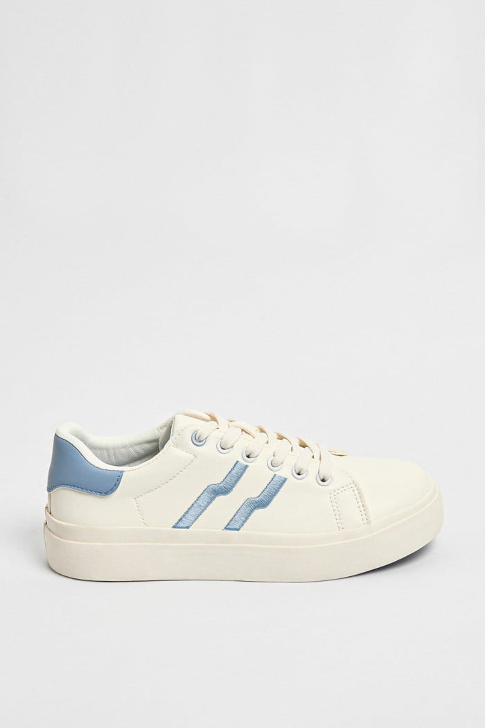 Tenis blancos casuales con contrastes azules y cordones