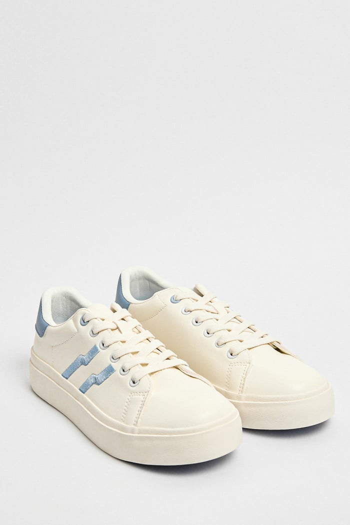 Tenis blancos casuales con contrastes azules y cordones