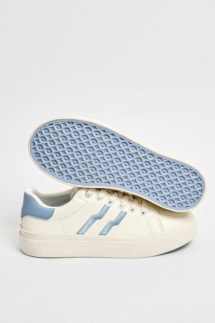 Tenis blancos casuales con contrastes azules y cordones
