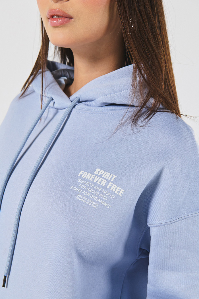 Buzo azul claro oversize con texto minimalista y capota