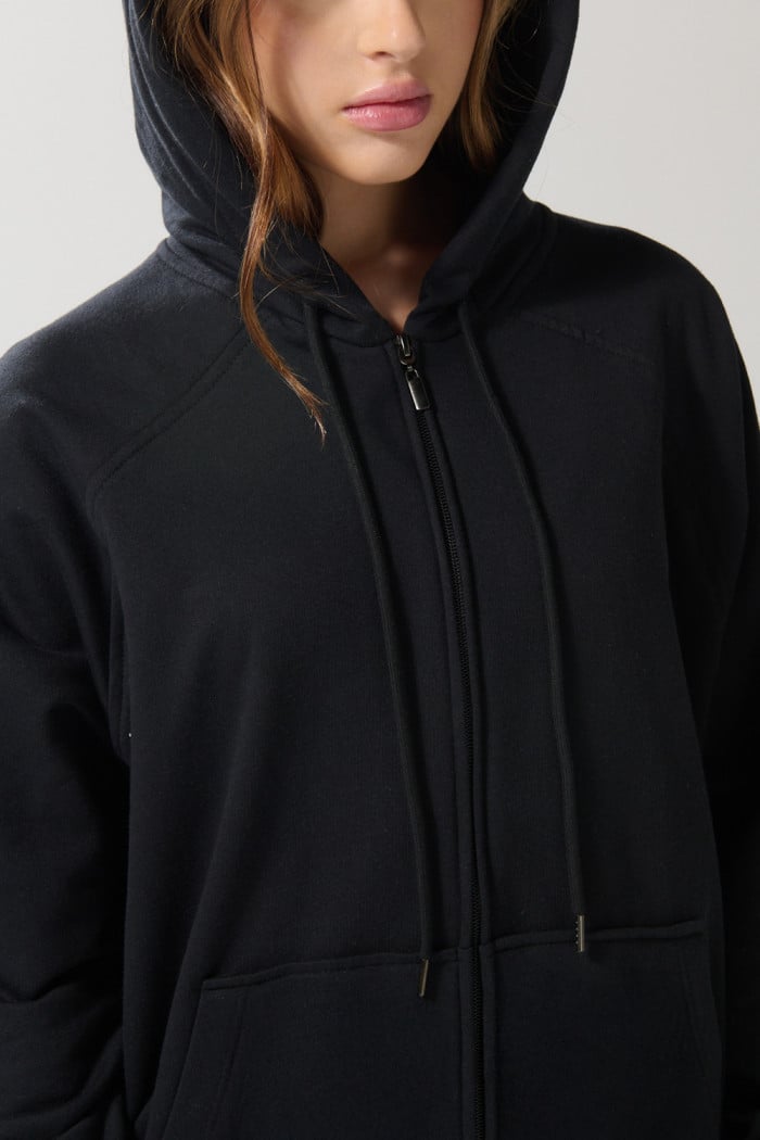 Buzo negro oversize con manga ranglan, capota y cremallera