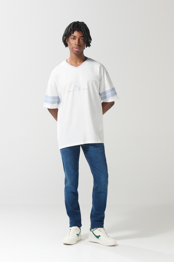 Camiseta crema cuello V con diseño college oversize