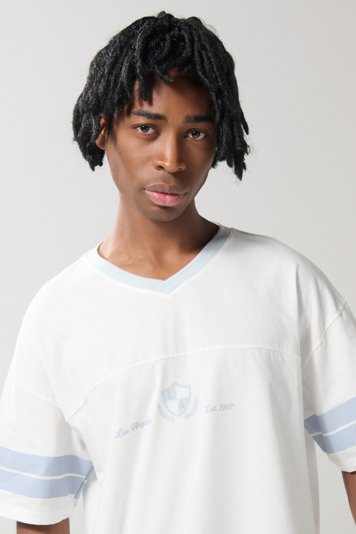 Camiseta crema cuello V con diseño college oversize