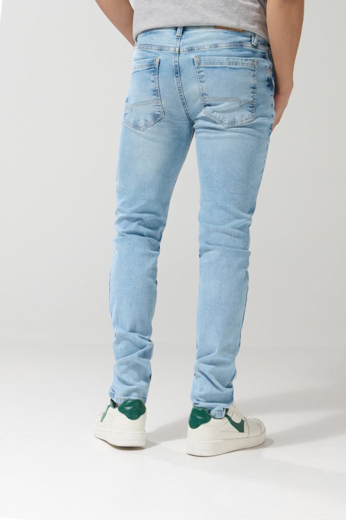 Jean azul claro skinny con desgastes localizados y tiro bajo