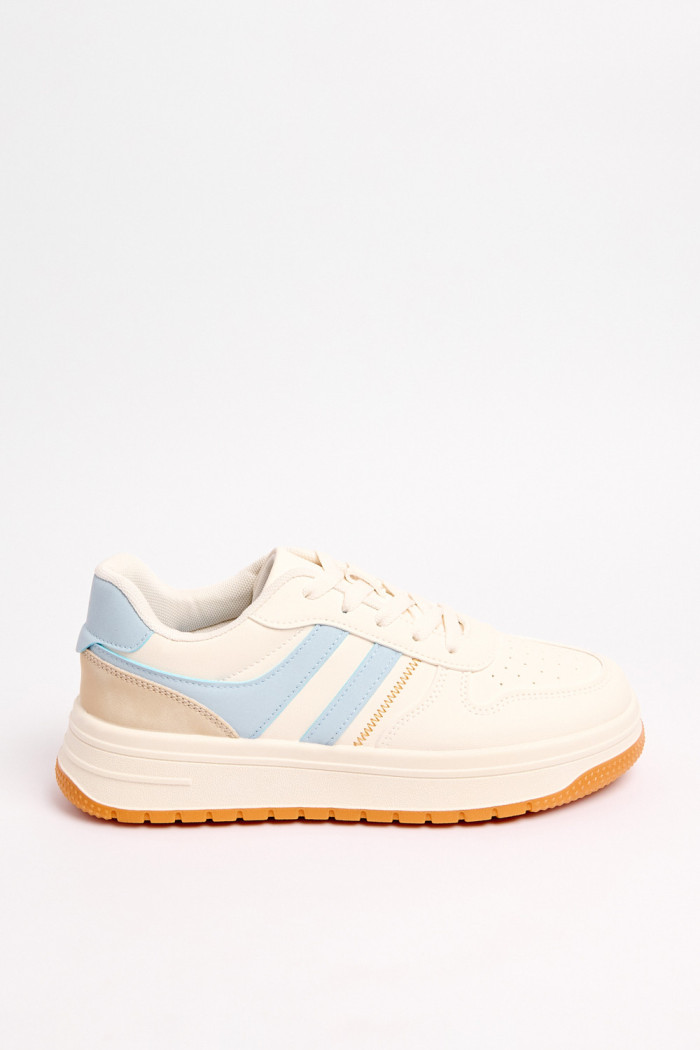 Tenis urbanos en color crema con contraste en azul claro y naranja.