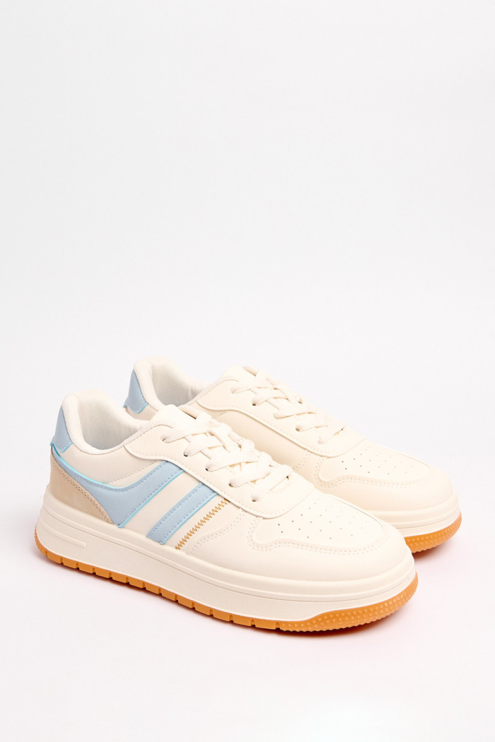 Tenis urbanos en color crema con contraste en azul claro y naranja.