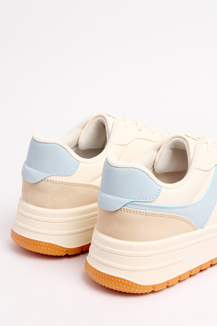 Tenis urbanos en color crema con contraste en azul claro y naranja.