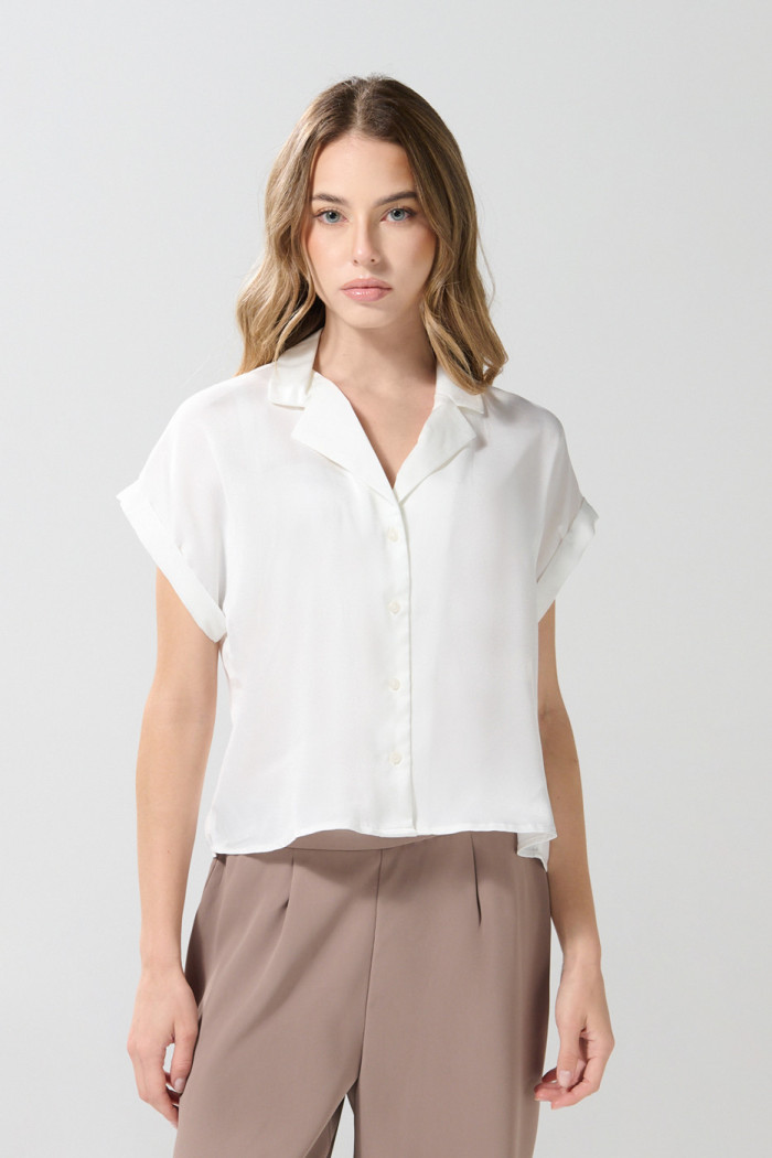 Blusa unicolor con manga corta, hombro rodado y botones