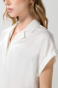Blusa unicolor con manga corta, hombro rodado y botones