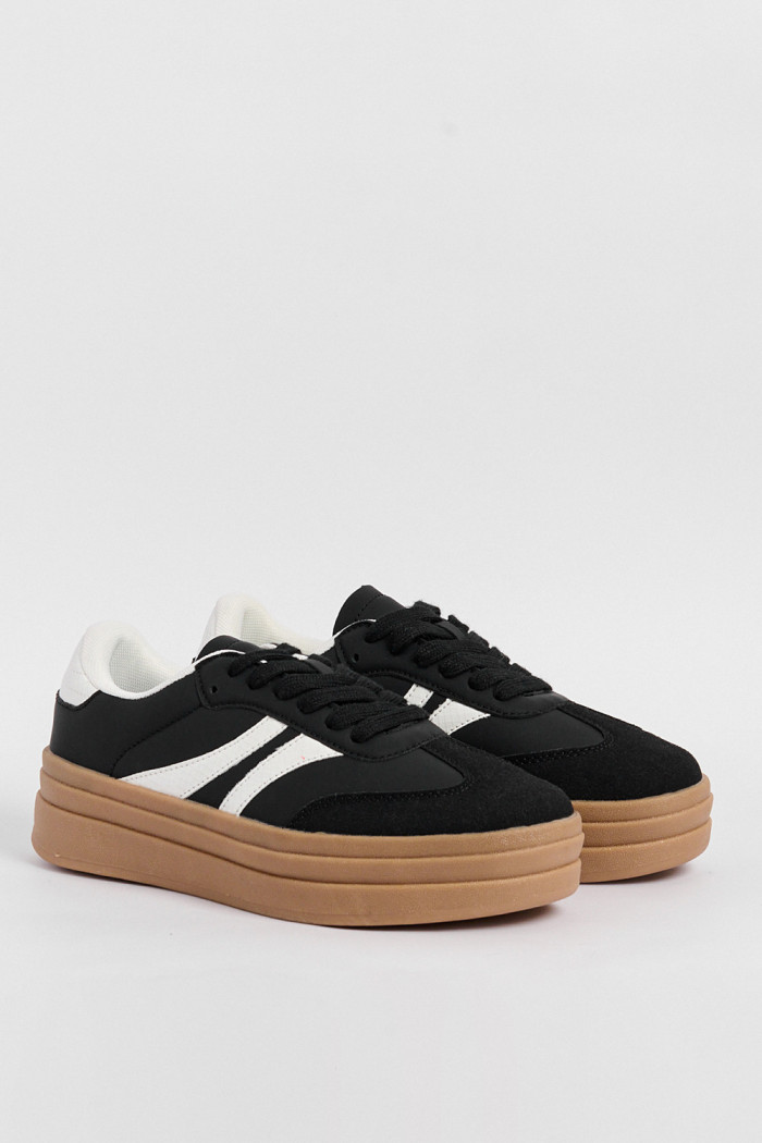 Tenis casuales negros con suelas altas planas y contrastes