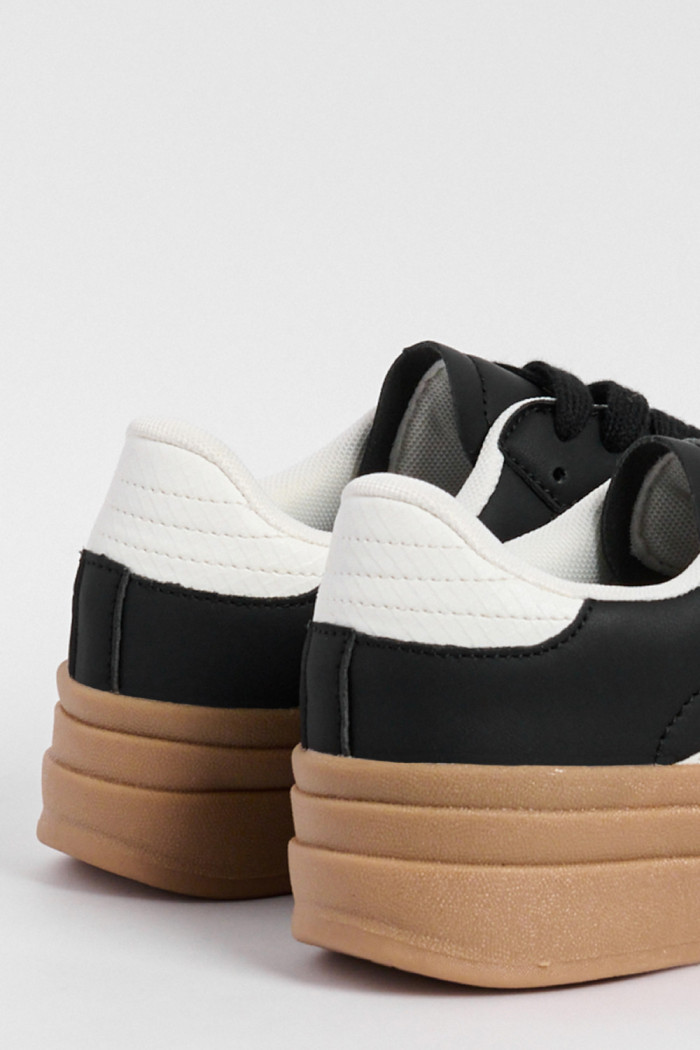 Tenis casuales negros con suelas altas planas y contrastes