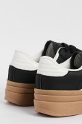 Tenis casuales negros con suelas altas planas y contrastes