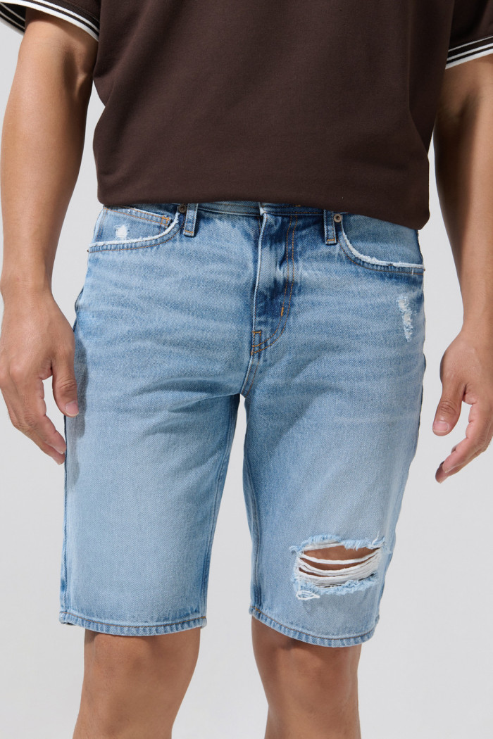 Bermuda de jean slim azul medio con rotos y tiro bajo