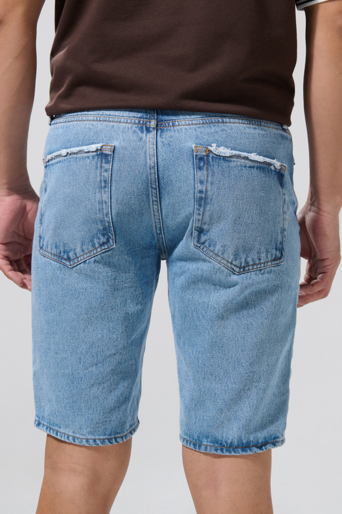 Bermuda de jean slim azul medio con rotos y tiro bajo